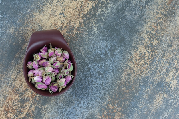 Petites roses en herbe dans un bol sombre.