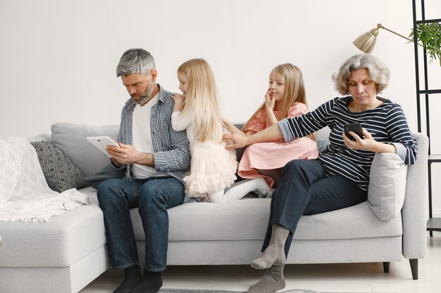 Petites soeurs assises sur le canapé avec leurs grands-parents.