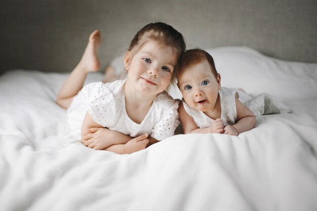 Petites soeurs du Caucase sont allongées sur la grande couverture blanche