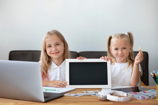 Petites soeurs faisant l'école en ligne ensemble à la maison