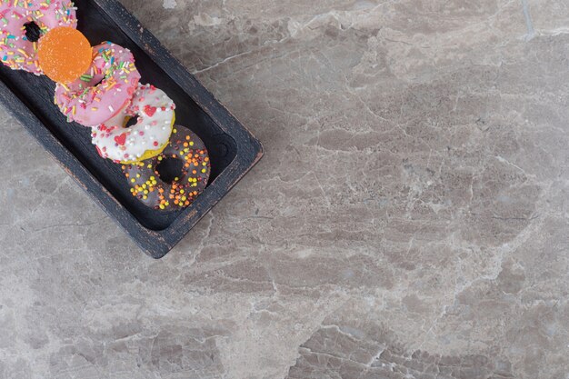 Petits beignets et marmelade empaquetés sur un plateau noir sur une surface en marbre