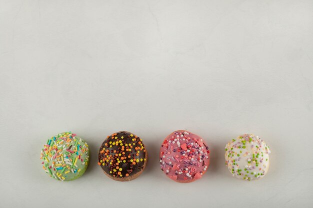 Petits beignets sucrés colorés sur une surface blanche.