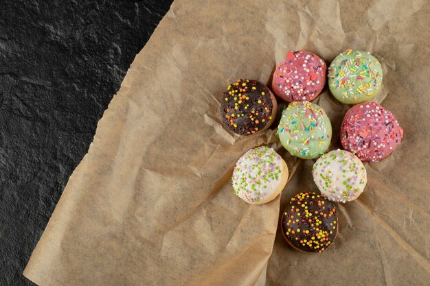 Petits beignets sucrés avec des paillettes sur un papier parchemin.