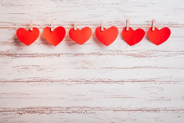 Petits cœurs en papier épinglés à une corde sur un mur