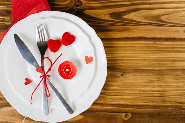 Petits coeurs rouges avec des couverts sur une plaque blanche