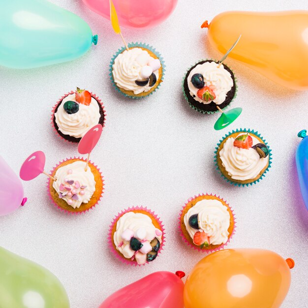 Petits cupcakes sucrés avec des ballons à air chaud sur table lumineuse