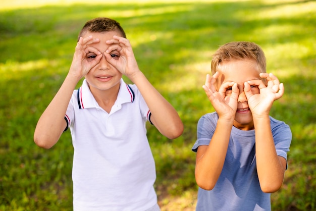 Petits garçons fabriquant de fausses lunettes avec leurs doigts