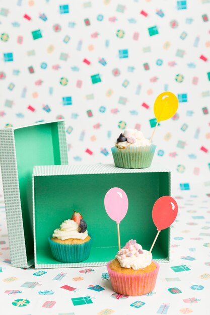 Petits gâteaux avec des ballons colorés sur la table