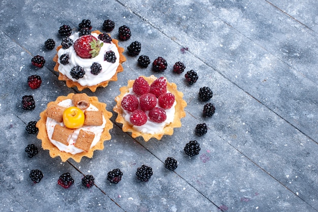 Photo gratuite petits gâteaux crémeux aux framboises avec des mûres en forme de coeur sur un bureau lumineux, biscuit gâteau aux baies de fruits