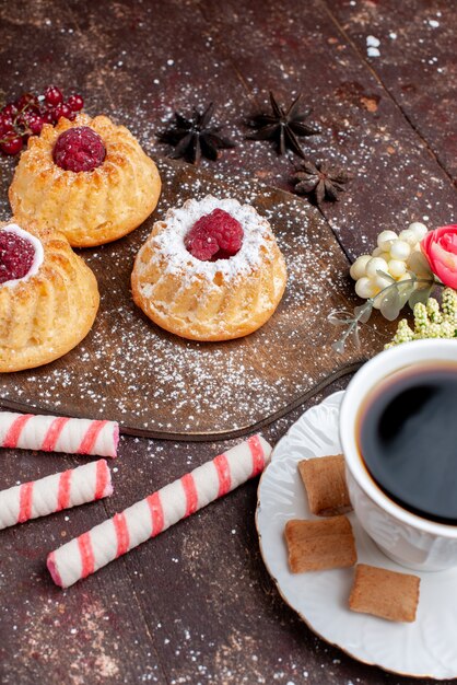 Petits gâteaux délicieux aux framboises avec bonbons bâton café sur un bureau en bois, gâteau aux fruits sucrés biscuit berry