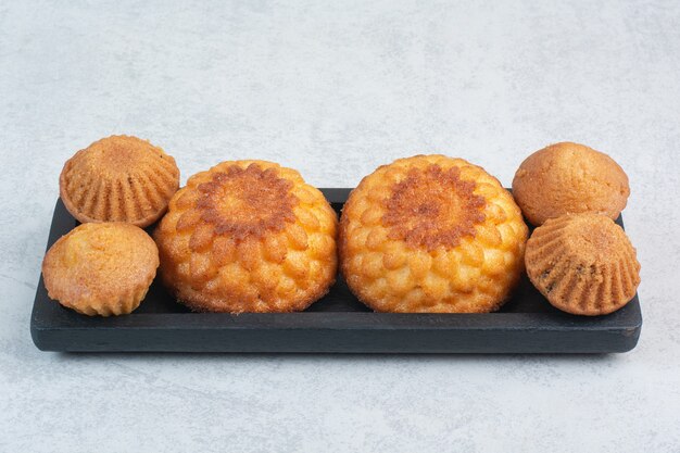 Petits gâteaux délicieux sucrés sur tableau noir