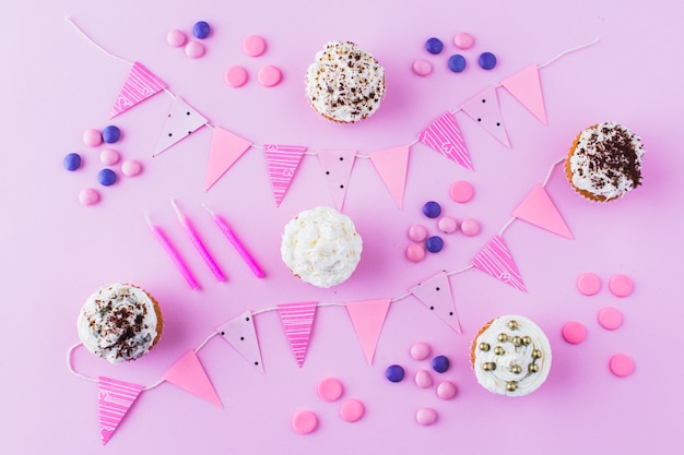 Petits gâteaux; des sucreries; bougies et banderoles sur fond rose