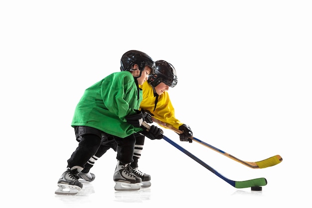 Photo gratuite petits joueurs de hockey avec les bâtons sur un court de glace et fond blanc.