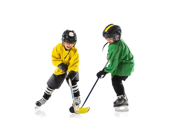 Petits joueurs de hockey avec des bâtons sur un court de glace et un mur blanc. Sportsboys portant des équipements et un casque pratiquant. Concept de sport, mode de vie sain, mouvement, mouvement, action.