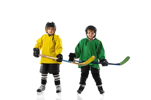 Petits joueurs de hockey avec les bâtons sur un court de glace et un mur de studio blanc