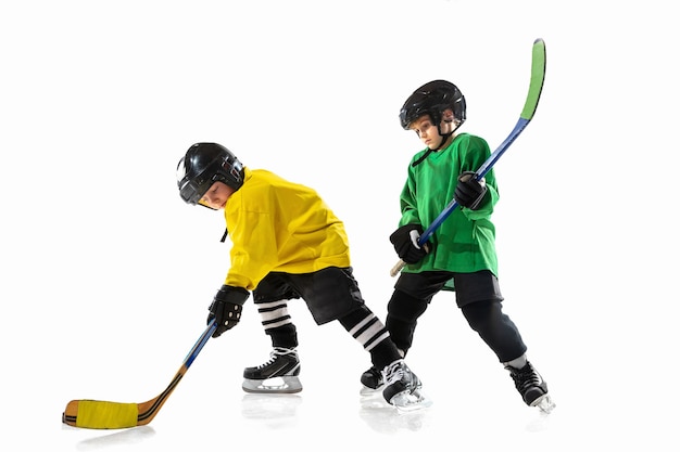 Petits joueurs de hockey avec les bâtons sur un court de glace et un mur de studio blanc