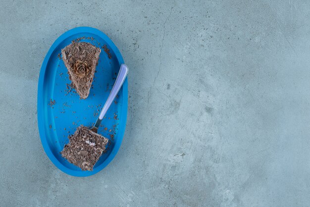 Petits morceaux de gâteau au chocolat et une fourchette sur un plateau bleu sur fond de marbre. Photo de haute qualité