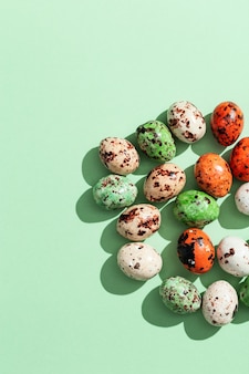 Petits œufs de caille colorés sur vert clair. vue de dessus fond de vacances de pâques printemps avec espace de copie
