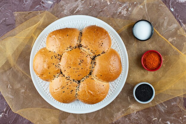 Petits pains blancs frais avec du sel et du poivre sur un fond clair.