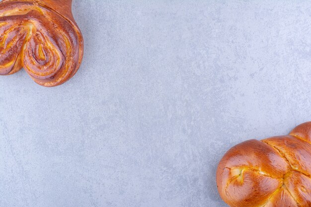 Petits pains coeur sucrés disposés de manière opposée sur une surface en marbre