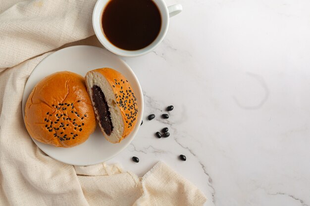 Petits pains à la pâte de haricots noirs cuits au four mis sur un bol blanc servi avec du café