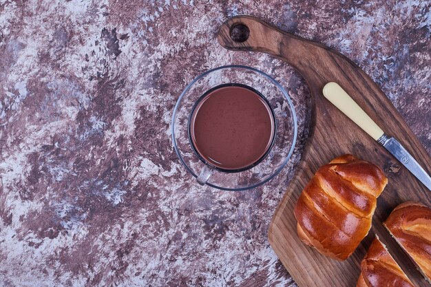 Petits pains sucrés sur une planche de bois avec une tasse de chocolat chaud. Photo de haute qualité