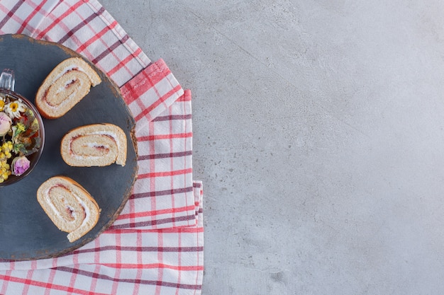 Petits pains sucrés à la vanille et tasse de thé sur morceau de bois.