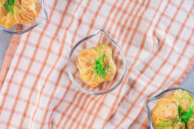 Petits plateaux en verre avec trois délicieux baklawas sur nappe