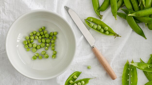 Petits pois à plat dans un bol avec un couteau