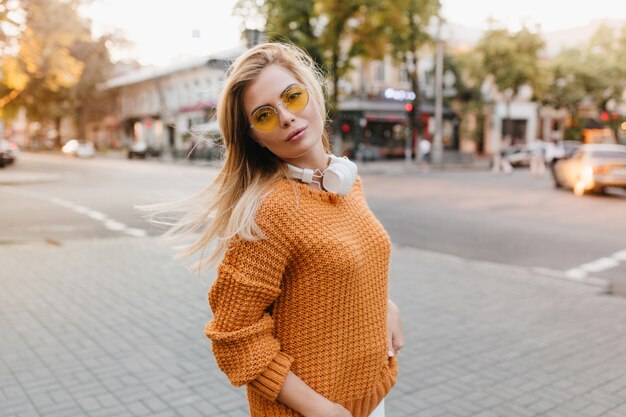 Peu de femme fatiguée en pull tricoté vintage marchant dans la rue