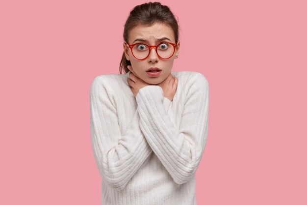 Peur de femme de race blanche tient les mains sur le cou tandis que cale de peur, se suicide, porte un pull blanc