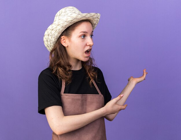 Peur jeune femme jardinier portant des points de chapeau de jardinage derrière