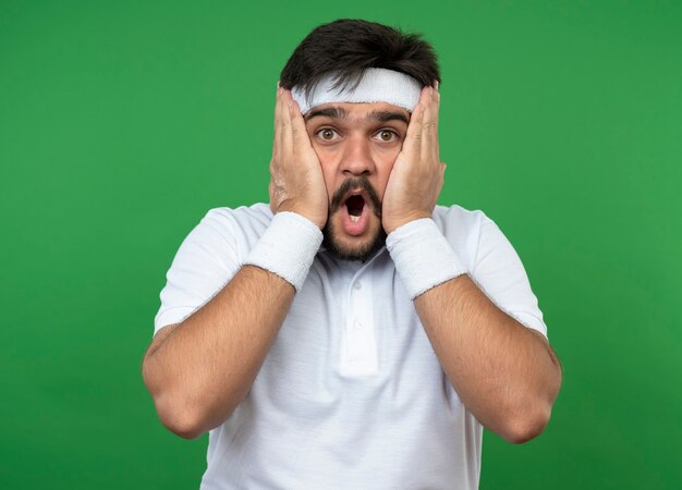 Peur de jeune homme sportif portant un bandeau et un bracelet visage couvert avec les mains