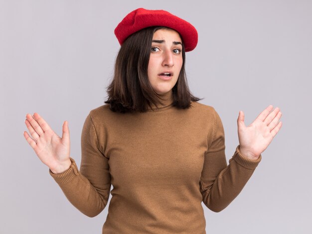 Peur jeune jolie fille caucasienne avec chapeau de béret debout avec les mains levées isolées sur mur blanc avec espace de copie