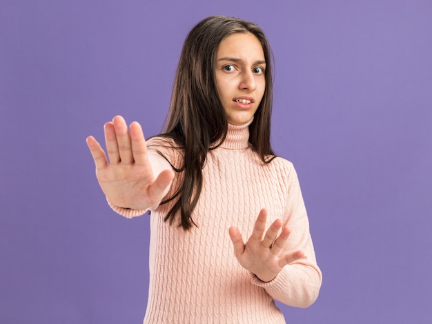 Peur jolie adolescente regardant la caméra faisant un geste de refus isolé sur mur violet avec espace de copie