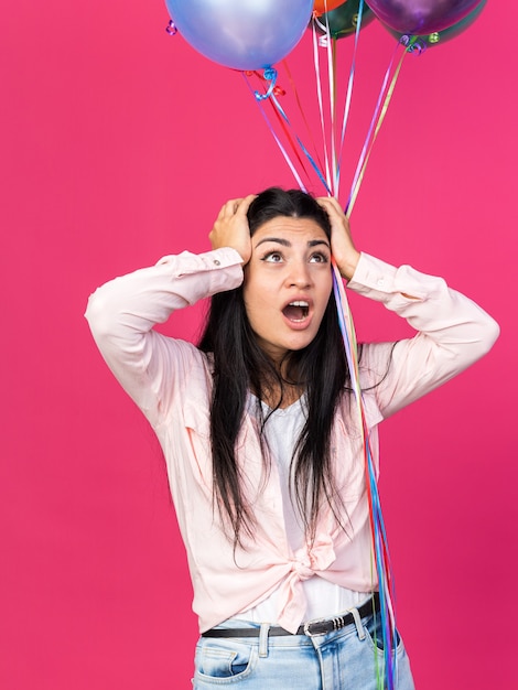 Peur en levant la belle jeune fille tenant des ballons attrapé la tête