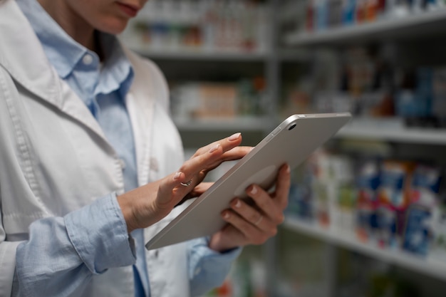 Photo gratuite pharmacien féminin avec table vérifiant le stock en pharmacie