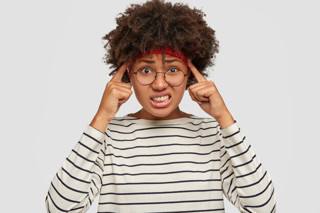 Photo d'une adolescente à la peau sombre stressée et mécontente garde les deux index sur les tempes