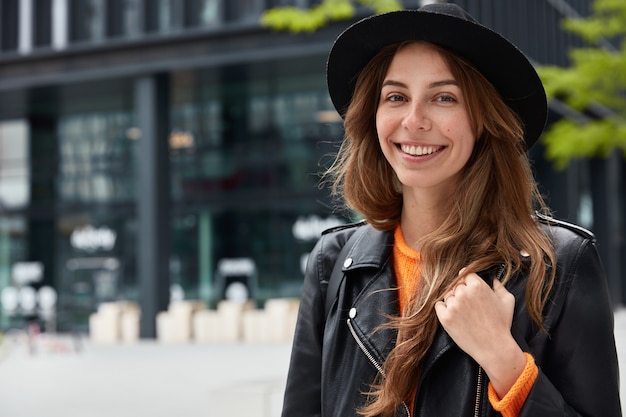 Photo d'agréable jeune femme touriste pose avec sourire heureux à la rue