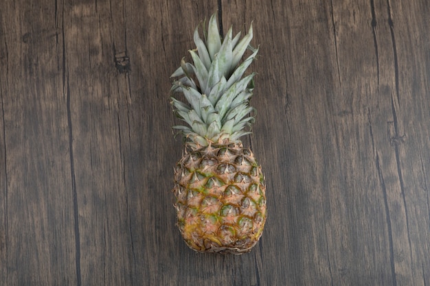 Photo d'ananas juteux mûr placé sur fond de bois
