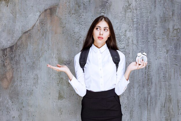 Photo d'une belle étudiante en tenue formelle montrant l'heure. Photo de haute qualité