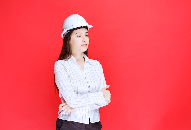 Photo d'une belle femme d'affaires portant un chapeau de sécurité debout avec les bras croisés.