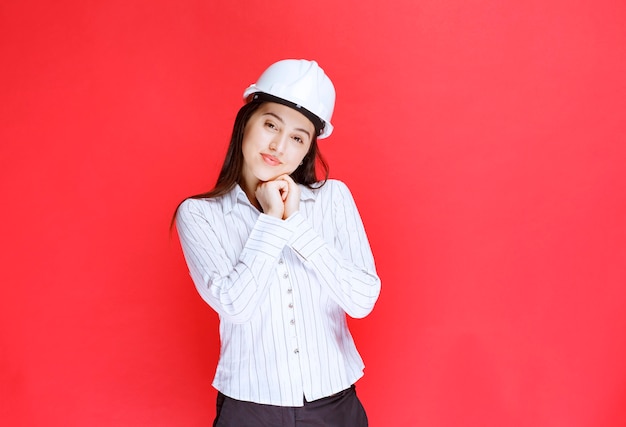 Photo D'une Belle Femme D'affaires Portant Un Chapeau De Sécurité Debout Contre Le Mur Rouge.