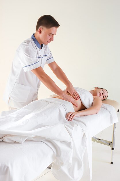 La photo de la belle femme dans le salon de massage et les mains des hommes sur son corps