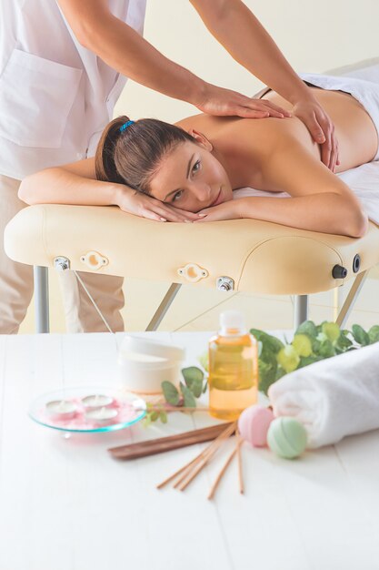 La photo de la belle femme dans le salon de massage et les mains mâles se bouchent