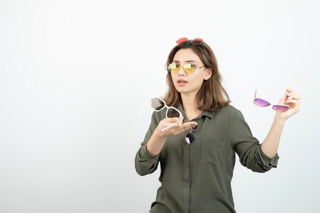 Photo de belle femme avec des lunettes de soleil colorées debout sur blanc. Photo de haute qualité