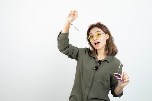 Photo de belle femme avec des lunettes de soleil colorées posant sur blanc. Photo de haute qualité