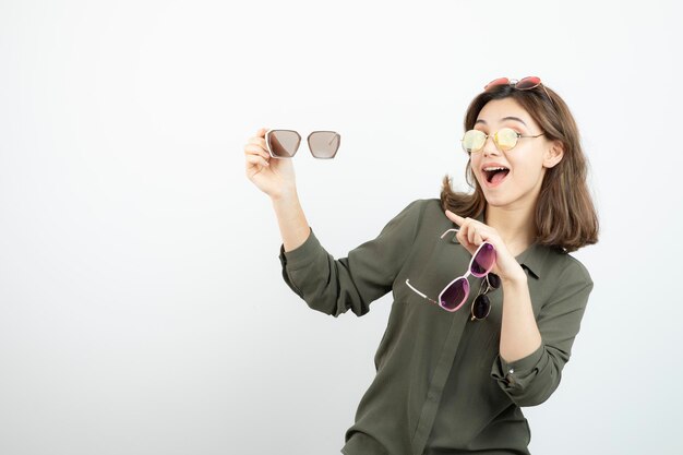 Photo de belle femme tenant des lunettes de soleil colorées sur blanc. Photo de haute qualité