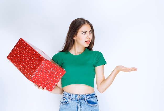 Photo de belle fille avec une boîte cadeau rouge debout sur fond blanc.