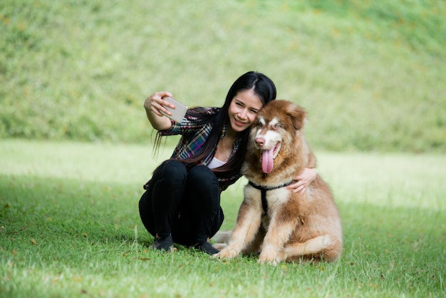 Photo de capture de belle jeune femme avec son petit chien dans un parc en plein air. Portrait de mode de vie.